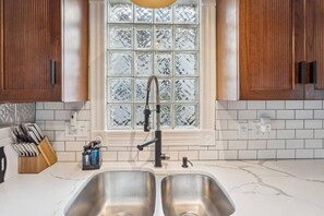 A kitchen with a double sink, wooden cabinets, a window with frosted glass, and a knife block. - Lakefront Retreat - Serene escape on Lake Erie! Amazing Views! Lorain OH (Lorain)