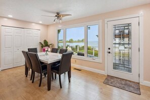 A dining area with a table and chairs, a ceiling fan, a view of a lake, and a door with a glass panel. - Lakefront Retreat - Serene escape on Lake Erie! Amazing Views! Lorain OH (Lorain)