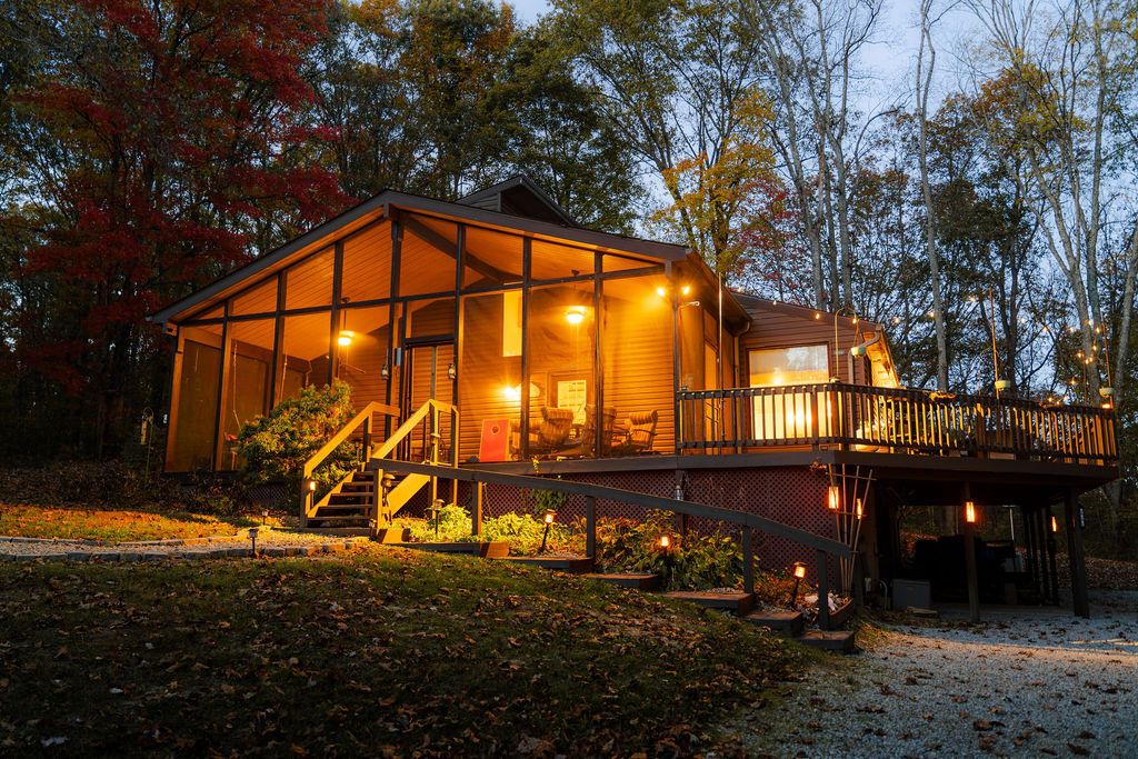 A cabin with a glass facade, a deck, and a staircase leading to the entrance.