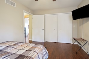 A bedroom with a bed, a TV, a wardrobe, and a door leading to another room.
