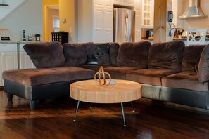 A sectional sofa with a round wooden coffee table in a living room with hardwood flooring.