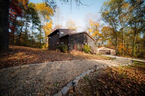 A modern house with a garage, surrounded by a gravel driveway and autumn foliage.