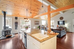 Una cocina espaciosa con una isla central, vigas de madera en el techo y un ventanal grande.
