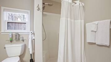 Ein Badezimmer mit Toilette, Dusche, einem Fenster und einem Handtuchhalter.