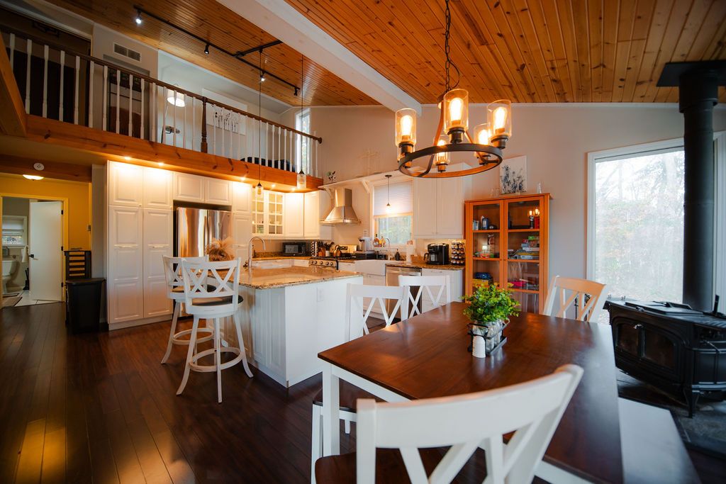 A spacious kitchen with a central island, white cabinetry, and a wooden ceiling.