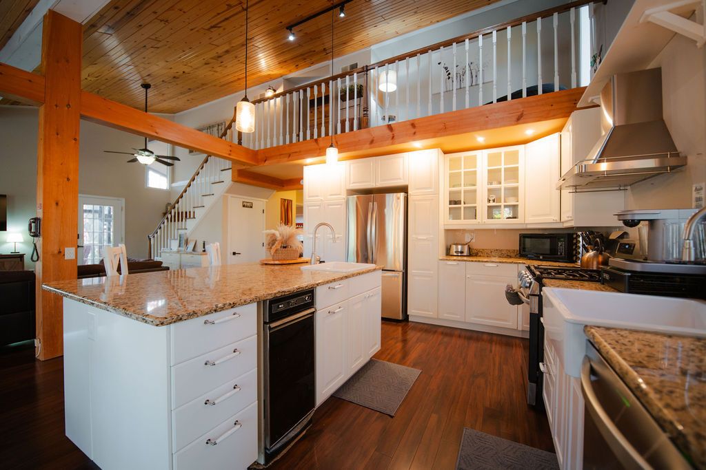 A spacious kitchen with a central island, white cabinetry, and a wooden ceiling.