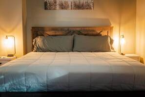 A bed with a wooden headboard, two bedside lamps, and a wall-mounted artwork.