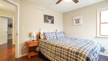 A bedroom with a bed, a nightstand, a ceiling fan, and two wall-mounted pictures.