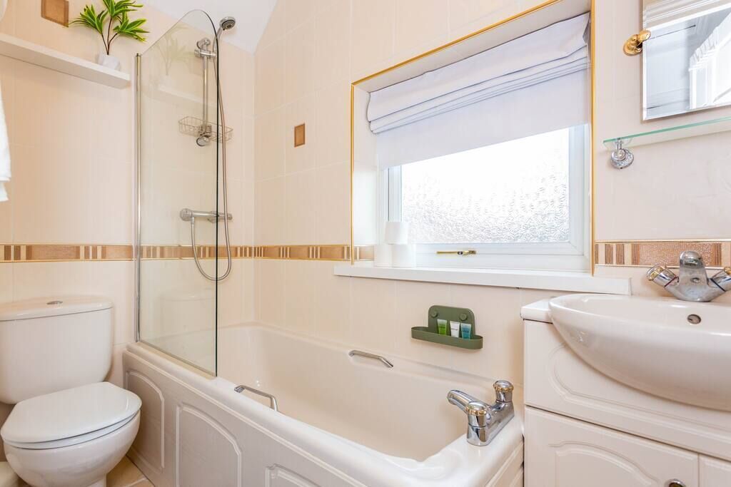 A bathroom with a glass-enclosed shower, a white toilet, a bathtub, and a sink with a mirror above it.