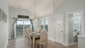 Un comedor con una mesa y sillas, un letrero sobre la mesa y vistas por la ventana.