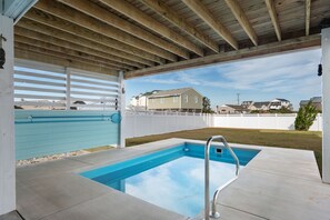Une piscine extérieure couverte, dotée d’un plafond en bois et offrant une vue sur les maisons situées au loin.