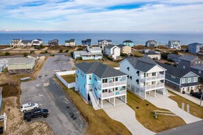 A coastal residential area with houses, a parking lot, and a view of the sea. - Ocean Breeze: Dog-Friendly w/Views, Elevator, Private Pool, Large fenced in Yard (Kitty Hawk)