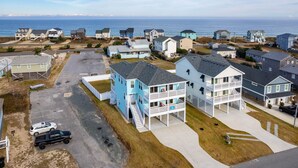 A coastal residential area with houses, a parking lot, and a view of the ocean. - Ocean Breeze: Dog-Friendly w/Views, Elevator, Private Pool, Large fenced in Yard (Kitty Hawk)