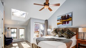 A bedroom with a large bed, a ceiling fan, a painting, and a view of the outdoors. - Ten Mile Townhouse in Downtown Frisco | Riverside! (Frisco)