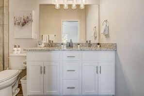 A modern bathroom with a white vanity, marble countertop, and a large mirror. - Rising Star (Colorado Springs)
