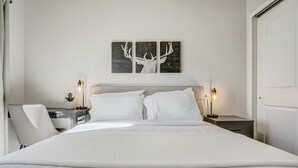 A modern hotel room with a large bed, two bedside tables with lamps, a headboard, and a wall-mounted deer artwork. - Rising Star (Colorado Springs)
