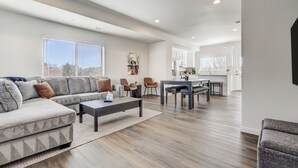A modern living room with a sectional sofa, a coffee table, and a dining area with a table and chairs. - Rising Star (Colorado Springs)
