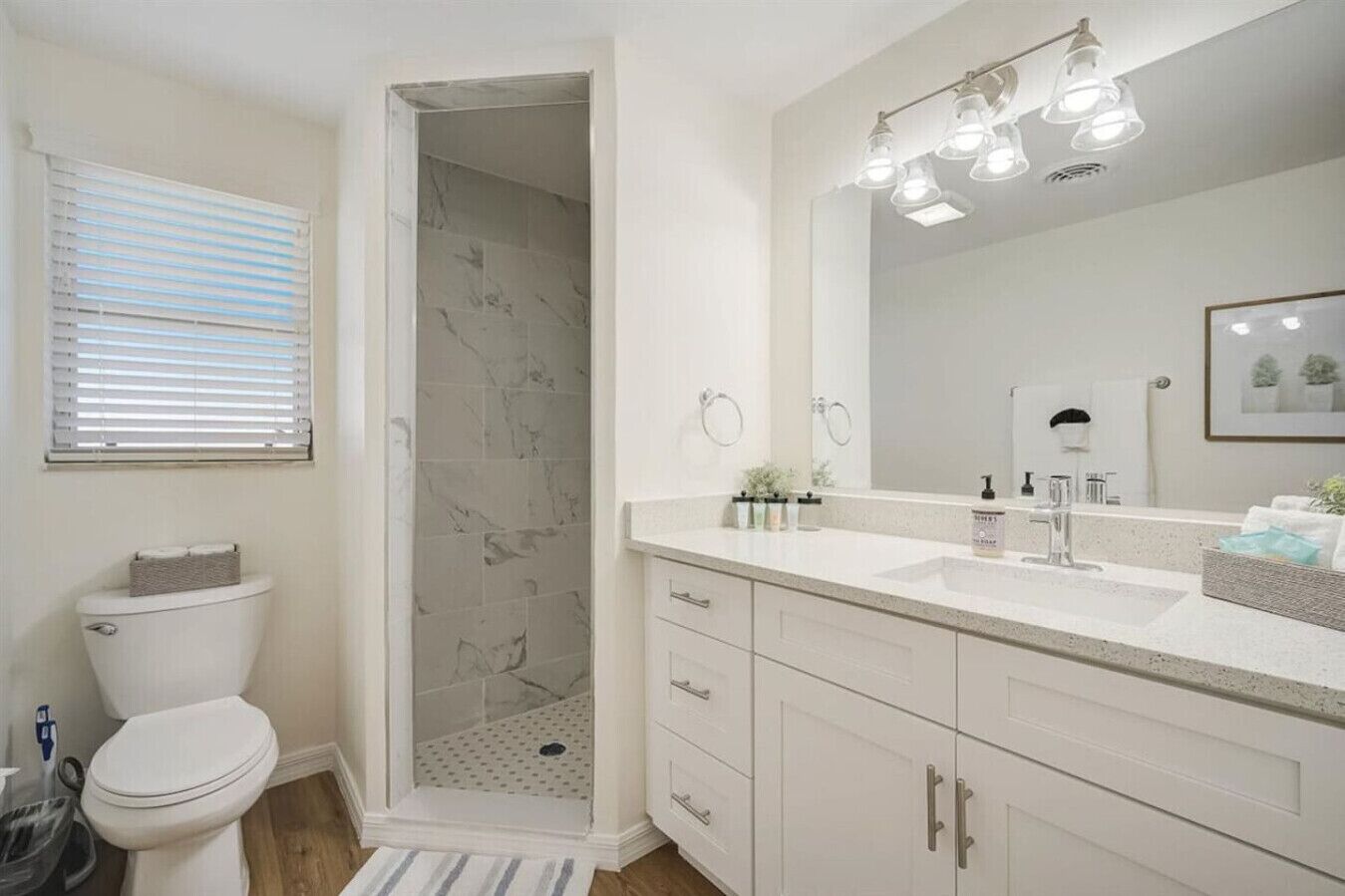 A bathroom with a shower, toilet, sink, and vanity.