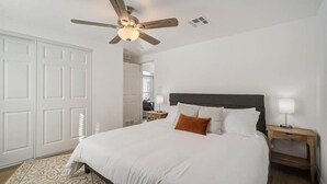 A bedroom with a bed, a ceiling fan, a nightstand with a lamp, and a patterned rug. - Spacious home With Heated Pool 3 miles from IMG! (Bradenton)