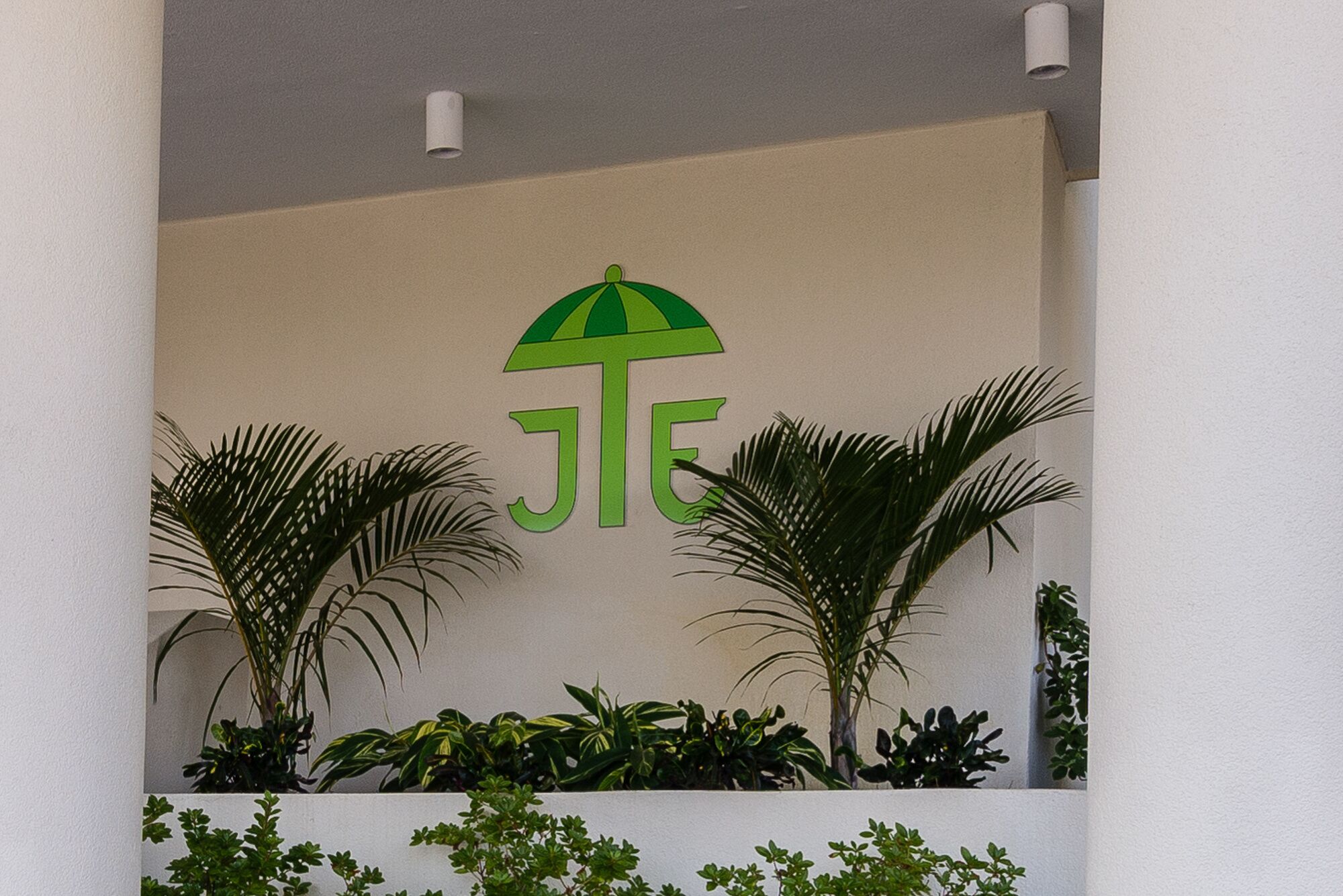 A wall with a logo and some plants.
