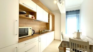 Eine moderne Küche mit weißen Schränken, einer Holz Arbeitsplatte, einer Mikrowelle und einem Spülbecken.