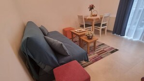 Ein Wohnzimmer mit einer Couch, einem kleinen Tisch mit einer Vase und einem roten Hocker.