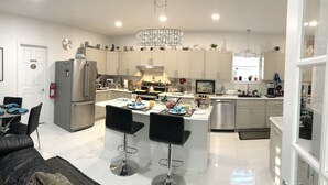 A modern kitchen with a central island, stainless steel appliances, and a chandelier. - Pleasant Street Inn (Parrsboro)