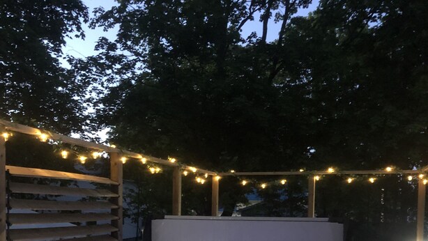 A hot tub with a wooden deck and string lights. - Pleasant Street Inn (Parrsboro)