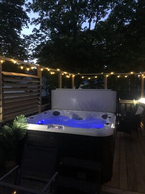 A hot tub with a wooden deck and string lights. - Pleasant Street Inn (Parrsboro)