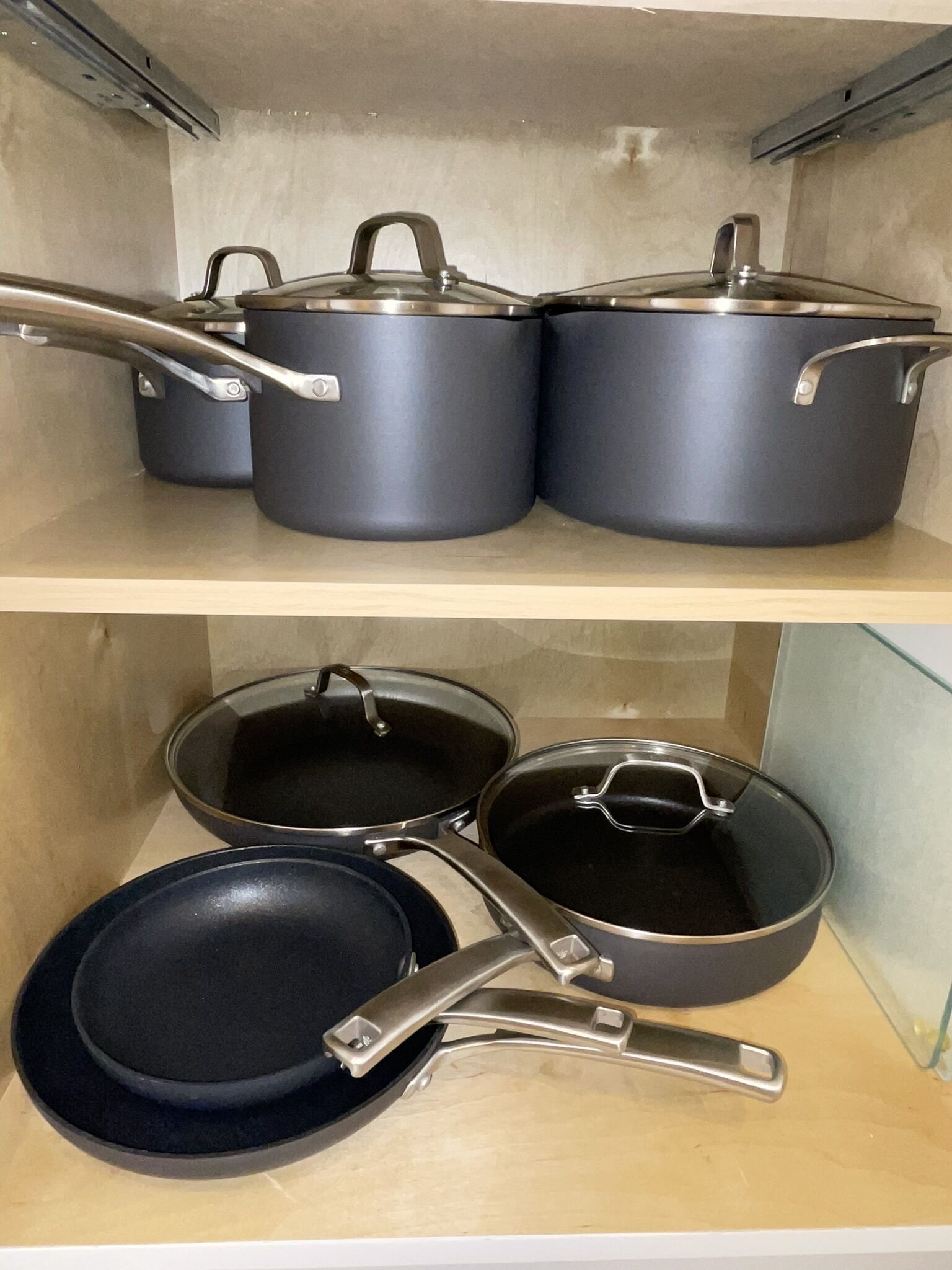 A kitchen with two shelves, each holding pots and pans.