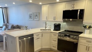 Una cocina moderna con armarios blancos, electrodomésticos de acero inoxidable y piso de madera.