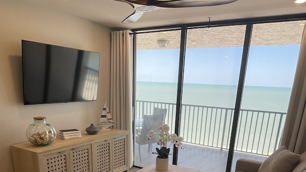 Una sala de estar moderna con un televisor grande, una mesa de centro de madera y un sofá.