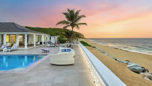 A resort with a pool, lounge chairs, and a beach view.