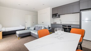 A modern, compact living space with a dining area, kitchenette, and two bedrooms. - Aurora City Suites Motel (Rotorua)
