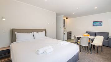 A hotel room with a bed, a desk, a chair, a sofa, and a painting on the wall.
