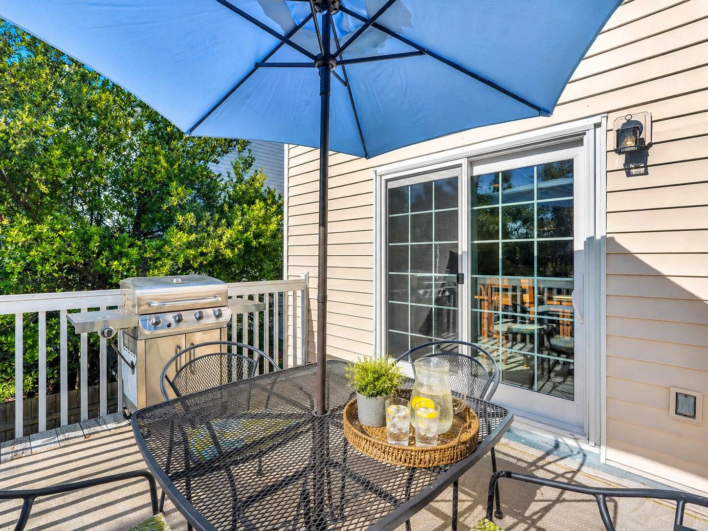 A patio with a grill, outdoor table, and umbrella.