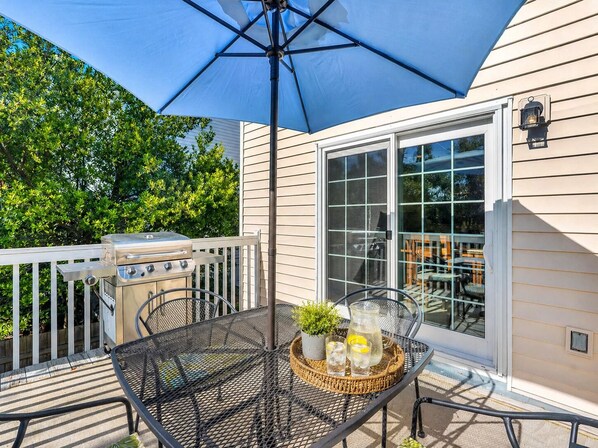A patio with a grill, outdoor table, and umbrella. - Private Courtyard + Walk to Beach, Restaurants & Shops | Quiet North Tybee Retreat | Sleeps 6 (Tybee Island)