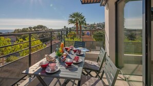 A balcony with a table set for a meal, overlooking a scenic landscape with trees and a clear sky. - Le Diamanti by Interhome (Saint Aygulf)