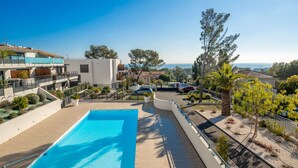 A swimming pool with a clear view of the surrounding buildings and a distant view of the sea. - Le Diamanti by Interhome (Saint Aygulf)
