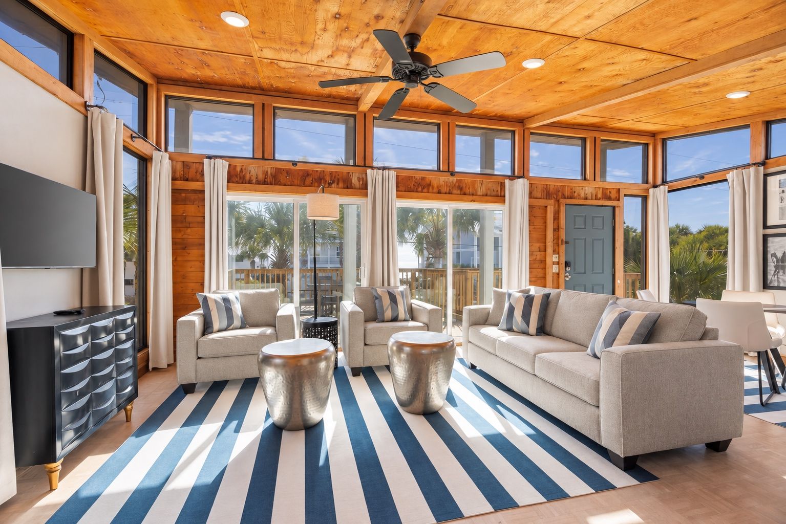 A spacious living area with a large sofa set, a TV, and a ceiling fan.