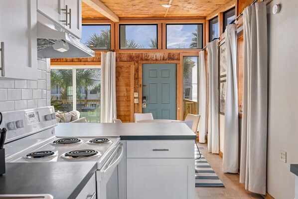 Een moderne keuken met een centraal eiland, een fornuis en een eethoek met uitzicht op palmbomen.