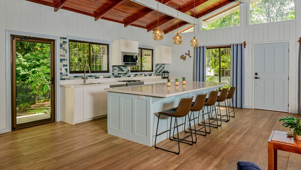 Una cucina moderna con un'isola grande, sgabelli da bar e vista sull'esterno.