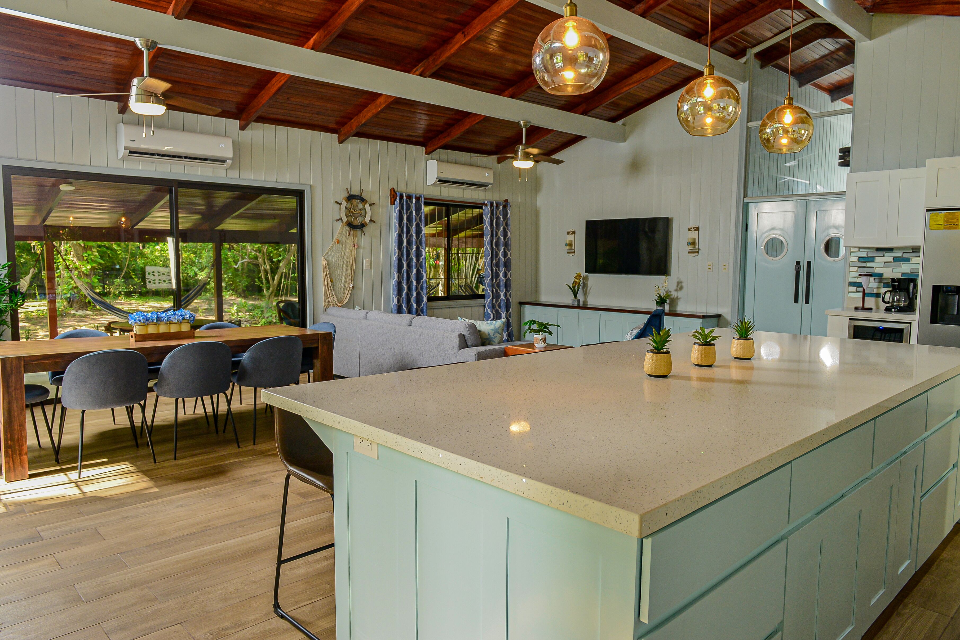 Une cuisine moderne dotée d’un grand îlot central, d’un plafond en bois et de luminaires suspendus.