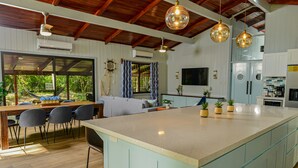 Una cucina moderna con una grande isola, soffitto in legno e luci a sospensione.