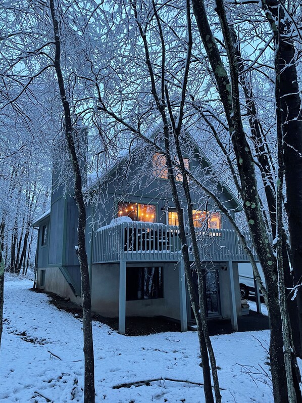 Una cabaña con balcón, rodeada de árboles cubiertos de nieve.