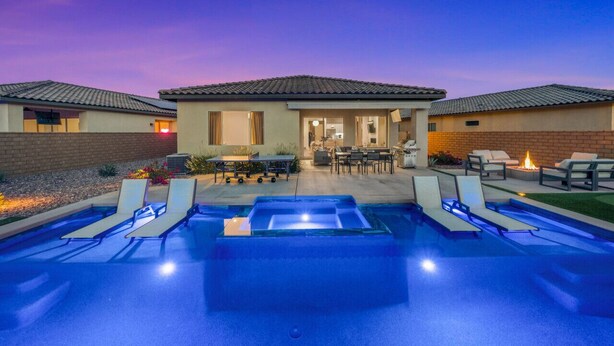 Ein modernes Haus mit Swimmingpool, Sitzgelegenheit im Freien und einer Feuerstelle.