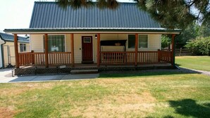 A single-story house with a covered porch, a front door, and a small attached garage. - Welcome to BarnRoots a Cozy Family sized house, bring your friends (Florence)