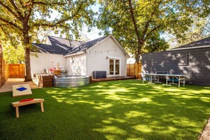A backyard with a hot tub, a wooden table, and a grassy lawn. - BACH! Heated Pool/Sleeps 10/Firepit/2miles DT, ACL (Austin)