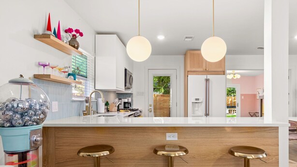 Een moderne keuken met een centraal eiland, barstoelen en hanglampen.