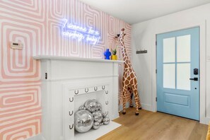 A room with a white fireplace, a blue door, and a giraffe decoration. - BACH! Heated Pool/Sleeps 10/Firepit/2miles DT, ACL (Austin)